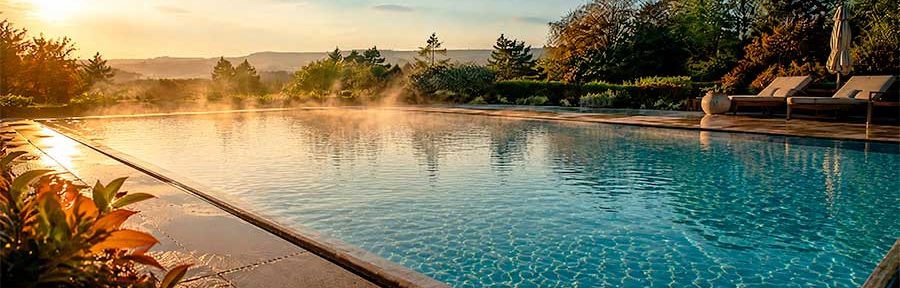 Piscine extérieure en été indien avec lumière dorée et végétation aux premières couleurs d’automne