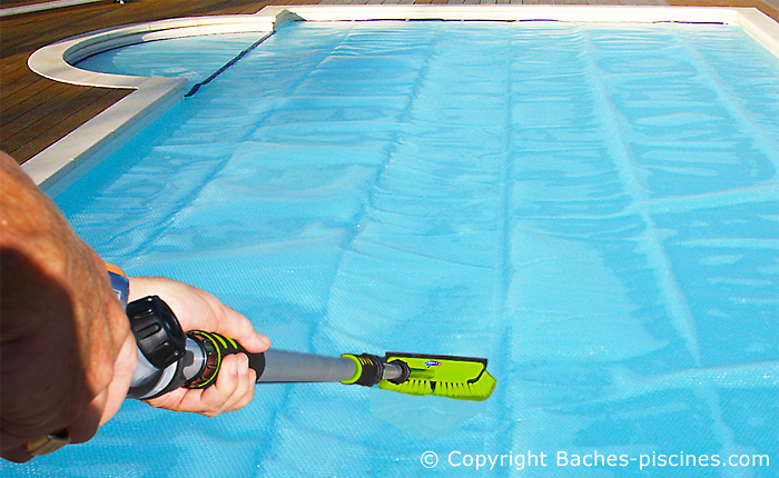 Brosse avec jet d'eau pour nettoyer une bâche piscine